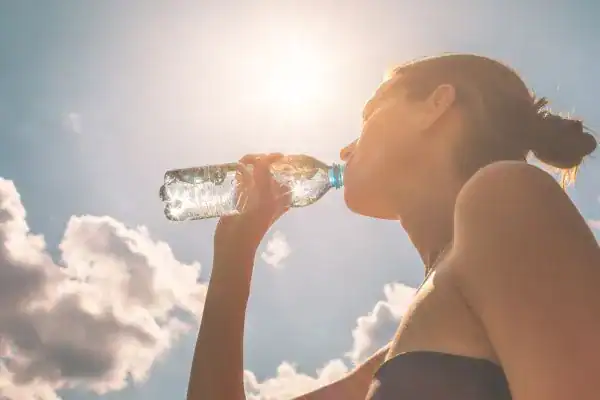 Image of woman drinking water to hydrate Halesowen after run.